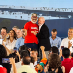 Funcionários da JBS de Campo Grande pedem ajuda a Lula por reajuste salarial durante discurso.